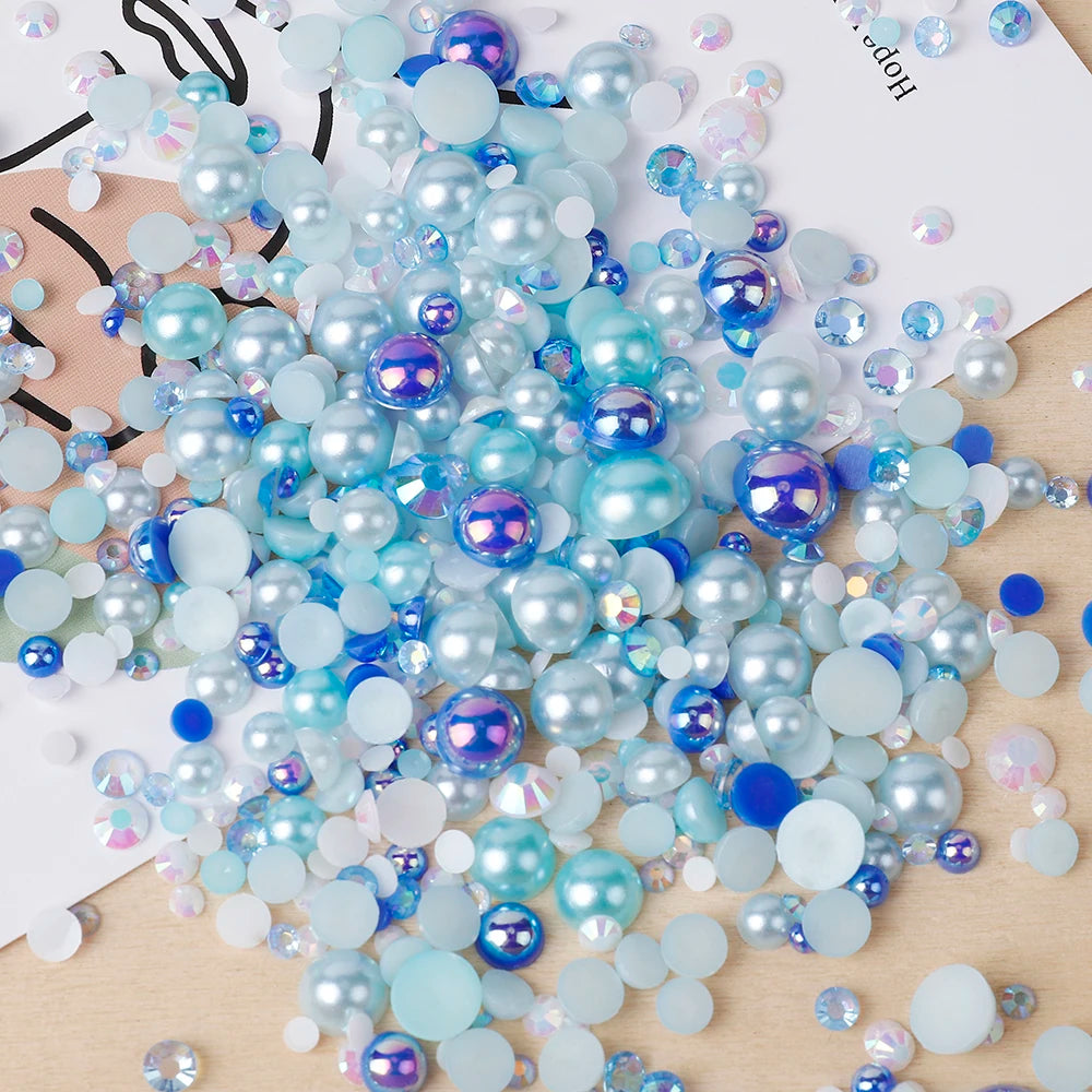 A scattered collection of mixed resin rhinestone pearls in various shades of blue and iridescent finish for crafts and nail a
