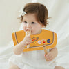 A baby is holding a yellow bib with a smile design, wearing a white outfit.
