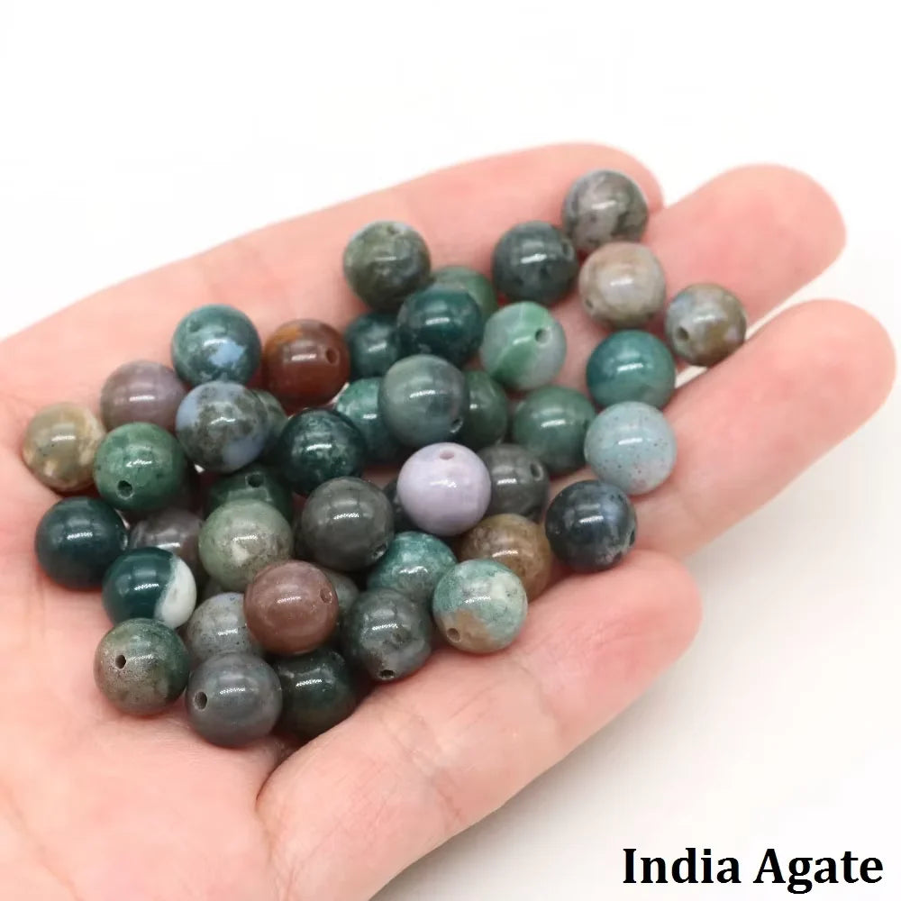 A handful of natural stone round beads including rose quartz, amethyst, and red silk jade for jewelry making