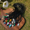 A collection of natural stone cross pendants and black wire, laid out on a wooden surface in grass.