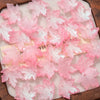 Pink maple leaf glass beads scattered on a wooden surface for DIY jewelry making