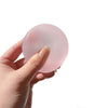 A hand holds a translucent pink strawberry mochi squishy stress relief toy.
