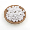 A pile of small white silicone round beads in a wooden bowl for jewelry making and crafts.
