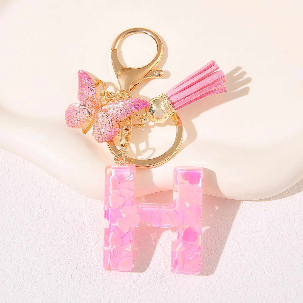 Gold initial H keychain featuring a pink butterfly charm on a white background.