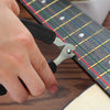 A hand is using a metal tool to wind or cut guitar strings on a fretboard.