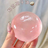 A hand holds a large, pink, translucent squeeze ball made of coconut oil for stress relief.