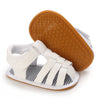 A pair of white baby first walker sandals with a brown anti-slip sole shown next to the shoe.