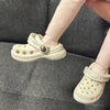 A pair of white fashion slippers for a doll are shown being worn on a person's foot.