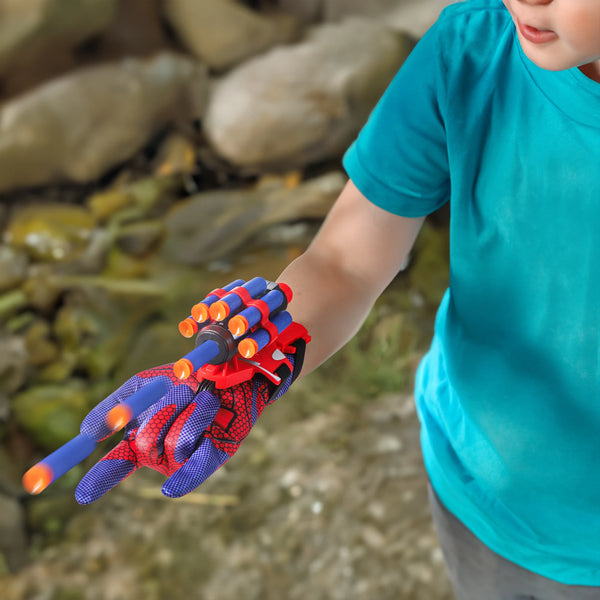 A child is wearing a red and blue cosplay spider dart glove set on their hand.