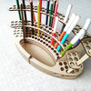 A wooden organizer holds numerous colored art brushes and pencils in individual slots.