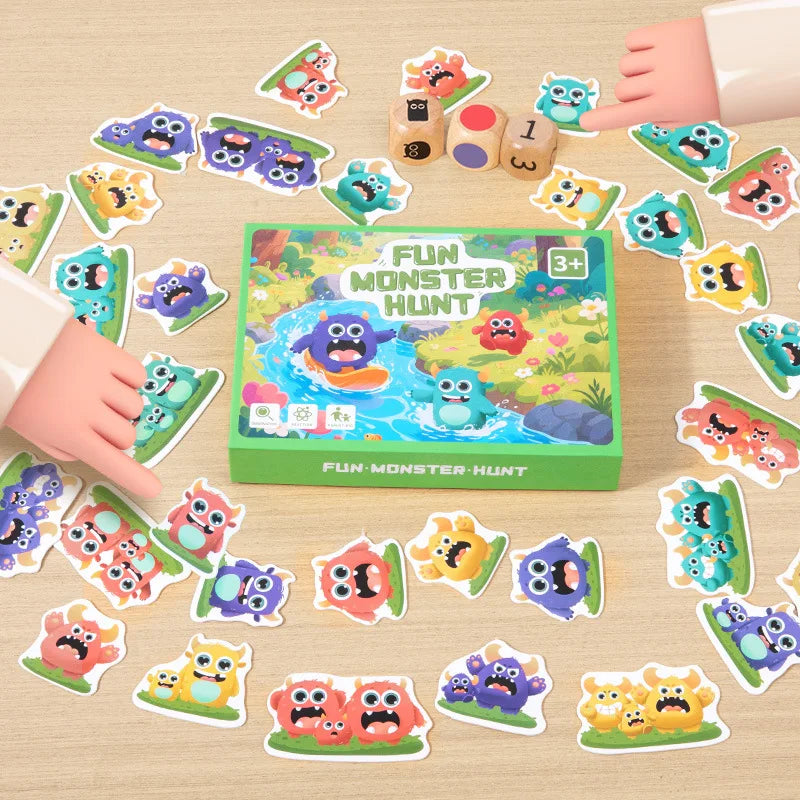 A hand is placing various monster-themed shape cards onto a green board game for kids.