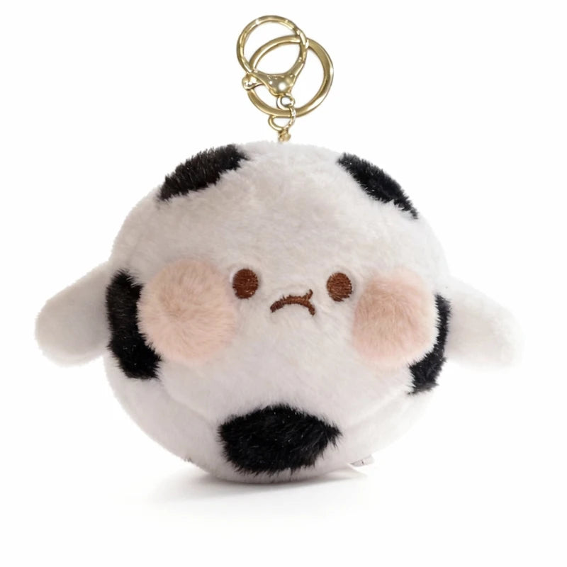 A white and black spotted plush character with a gold-colored keychain attached.