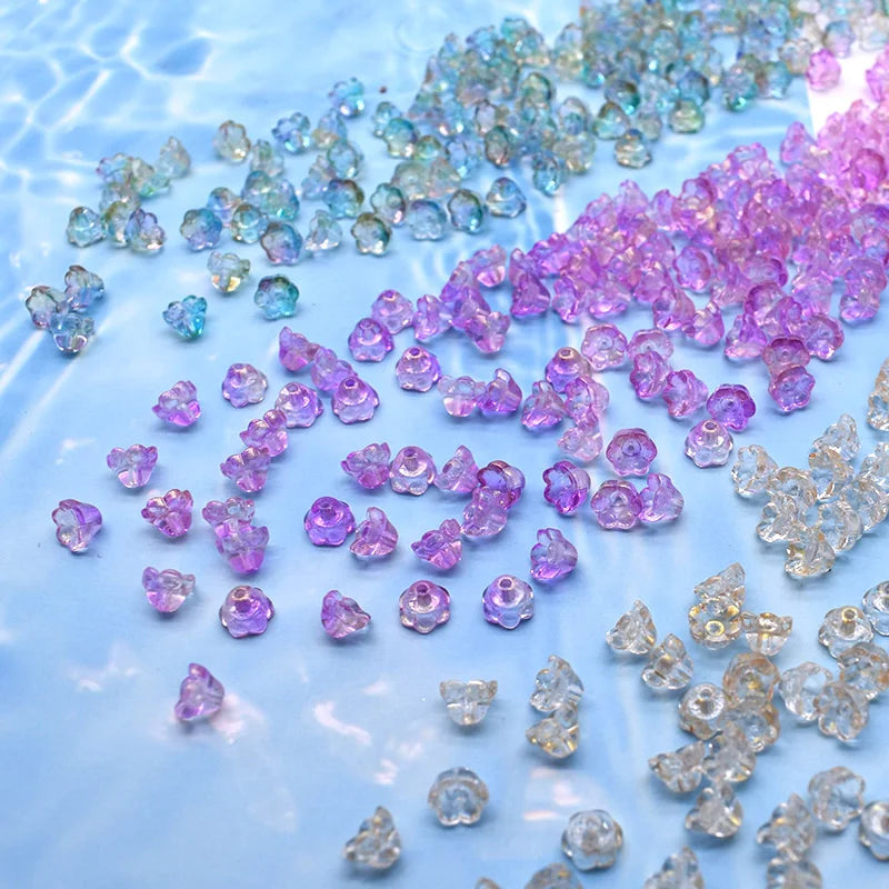 A collection of colorful glass beads in shades of blue, purple, and pink scattered across a light blue surface.