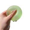 A hand holds a translucent light green squishy stress relief toy shaped like a mochi ring.