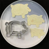 A set of pig-shaped stainless steel cookie cutters on a white plate.