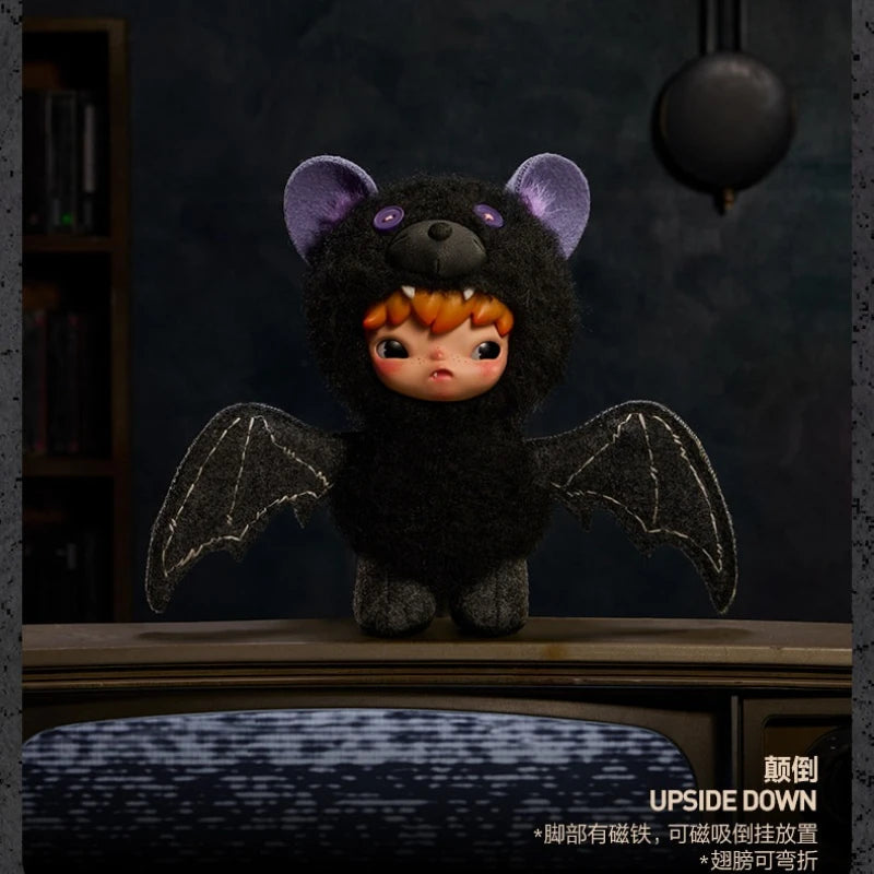 A dark plush doll with purple ears and black wings is displayed on a wooden surface.