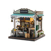 A detailed wooden miniature coffee shop house kit featuring a counter, seating area, and signage.