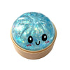 A round, translucent blue squishy fidget toy with a cute face design and glitter inclusions.