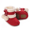 A pair of red and white faux fur baby winter boots for first walkers with a decorative bow detail.