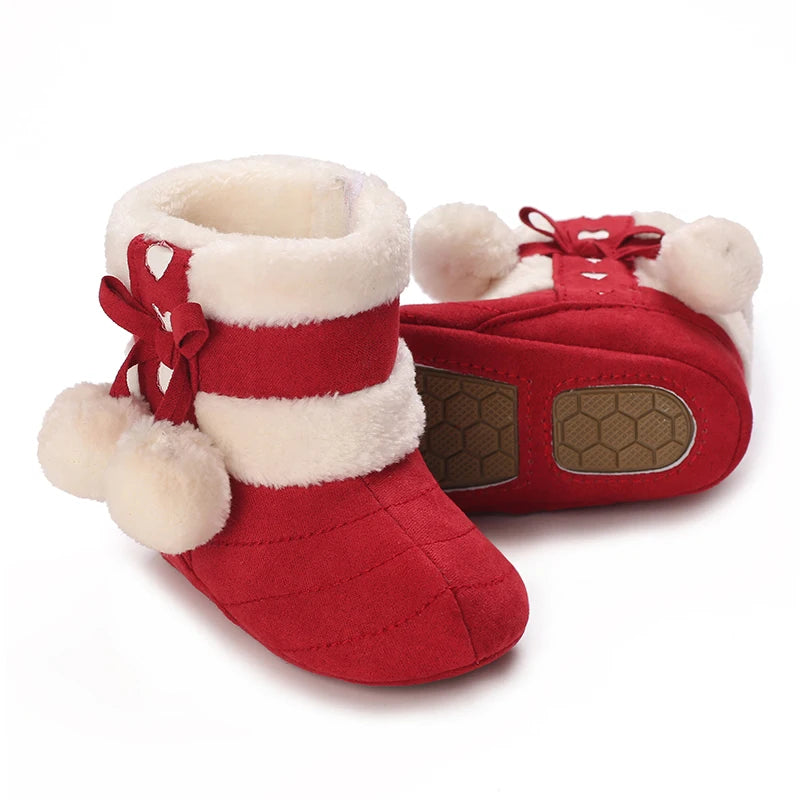 A pair of red and white faux fur baby winter boots for first walkers with a decorative bow detail.