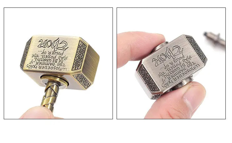 A close-up view of a hammer-shaped metal fidget spinner with engraved text and a removable pin.