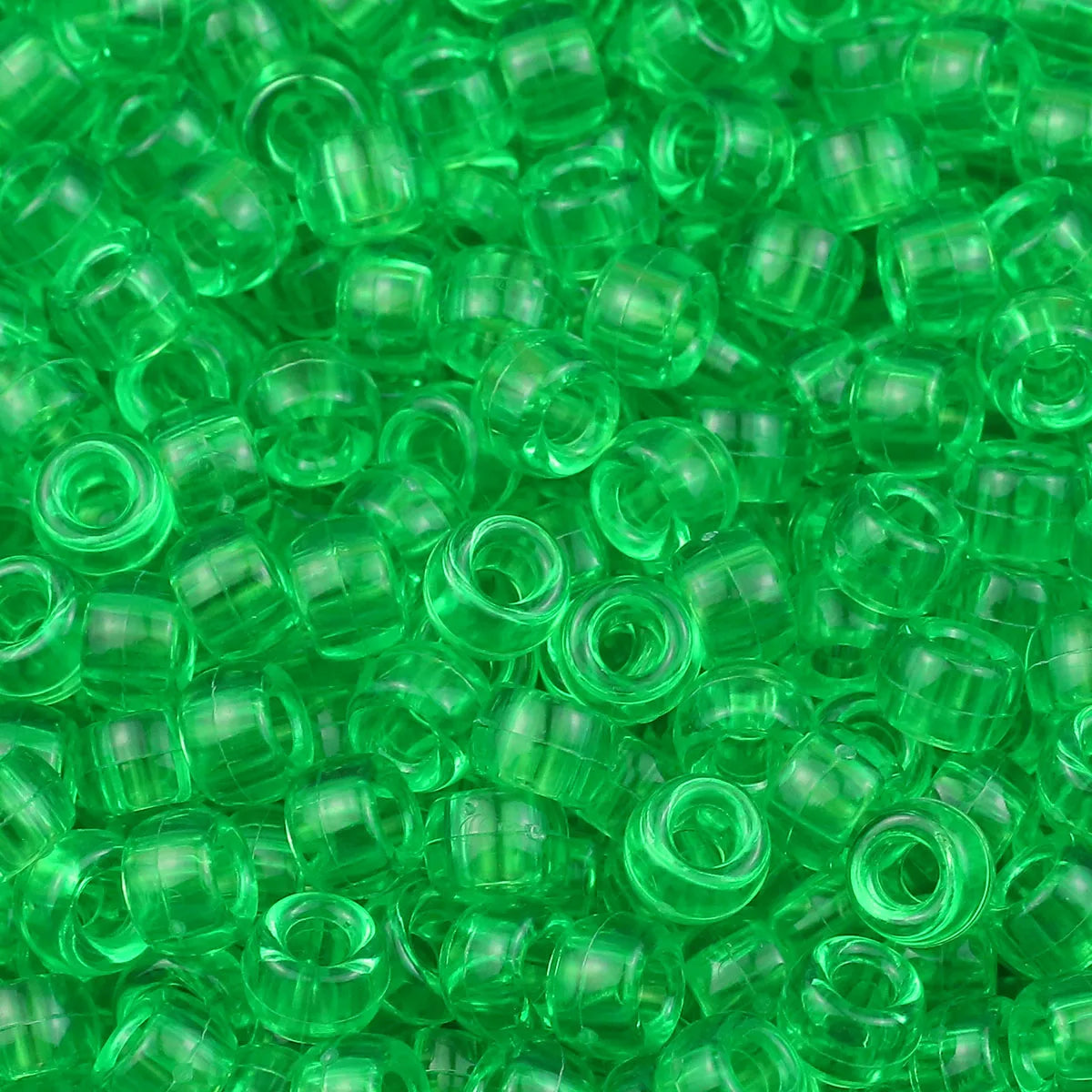 A close-up view of small, solid green pony beads for jewelry making and craft projects.