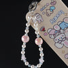 A silver charm featuring pink and clear pearl crystals attached to a bag clip, displayed against a light-colored phone case.