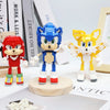 A set of three stylized dinosaur building block figures in red, blue, and yellow standing on a wooden base.