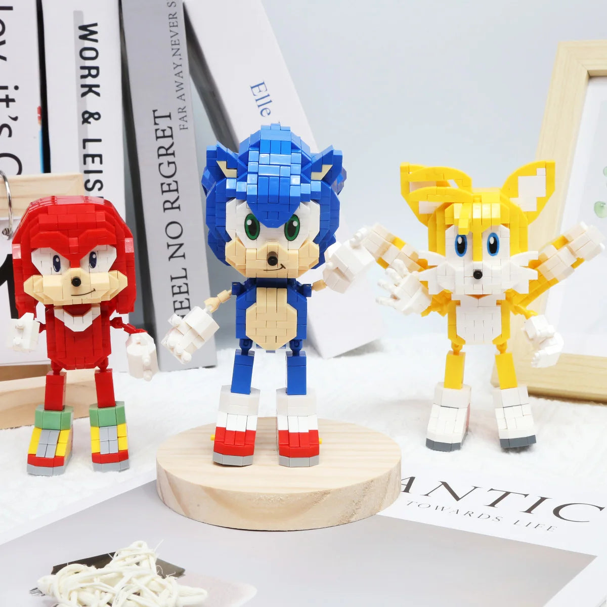 A set of three stylized dinosaur building block figures in red, blue, and yellow standing on a wooden base.