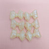 A collection of translucent, pale yellow shimmer mermaid bowknot beads for jewelry making.
