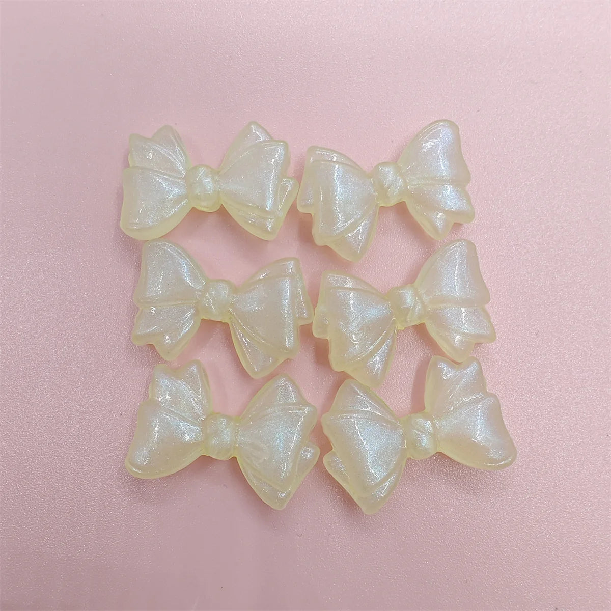A collection of translucent, pale yellow shimmer mermaid bowknot beads for jewelry making.