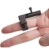 A hand holds a dark brown finger ring launcher keychain fidget toy with a small metal pin.
