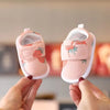 A pair of pink bear soft sole first walker shoes for babies being held by a hand.