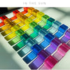 A collection of colorful rainbow acrylic building blocks arranged in a diagonal pattern under sunlight.