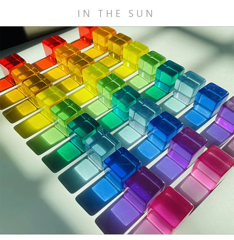 A collection of colorful rainbow acrylic building blocks arranged in a diagonal pattern under sunlight.