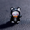 A small black and white cartoon bear figurine with pink cheeks and an orange bowtie.