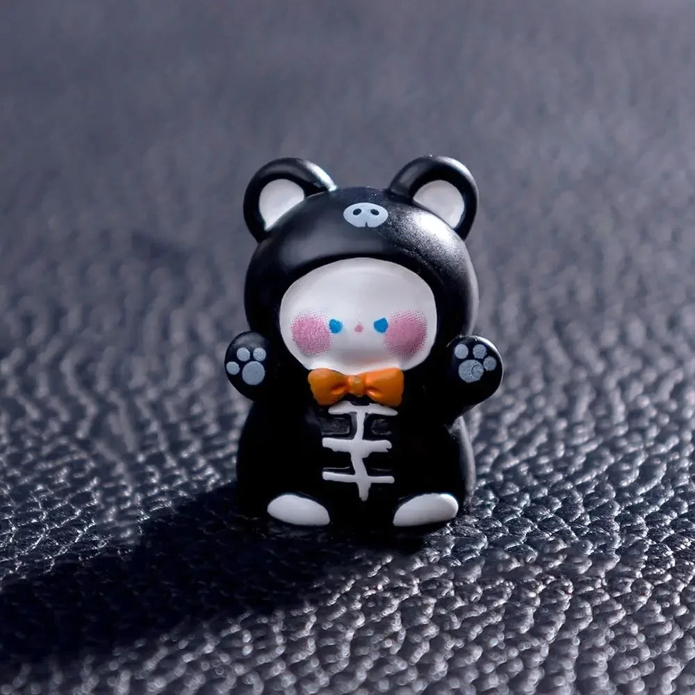 A small black and white cartoon bear figurine with pink cheeks and an orange bowtie.