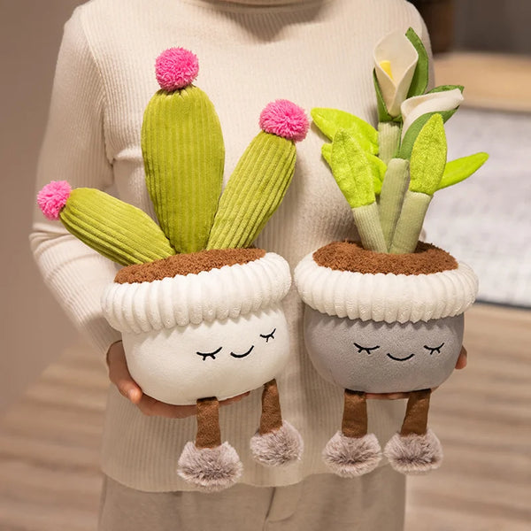A hand holds a plush decoration featuring a cactus and a flower arrangement with pink pom-poms.