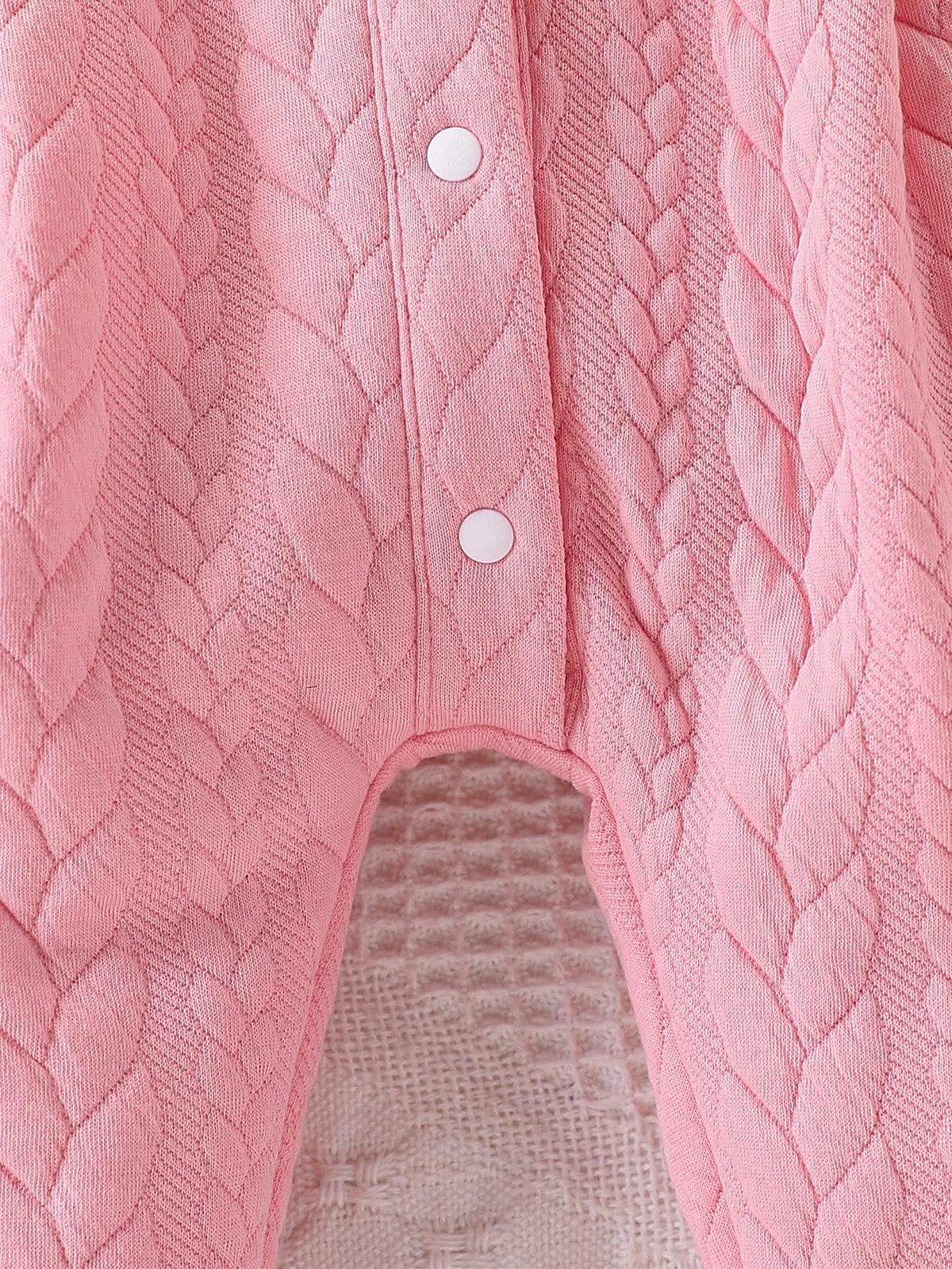 Pink quilted baby girl romper featuring a lace collar and button details.