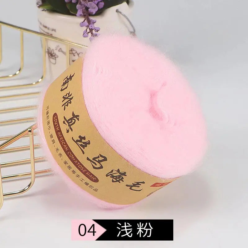 Pink mohair blended yarn for knitting shawls and sweaters displayed next to a gold wire rack.