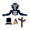 A dark gray and black plush toy of a monkey with large eyes and a small hat and branch accessory.