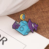 A set of enamel pins featuring a dragon and a skull design on a blue background.