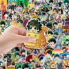 A hand holds a yellow My Hero Academia anime decal sticker against a background of various anime characters.