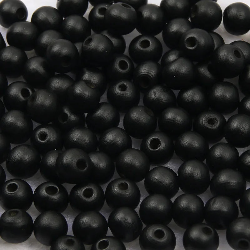 A pile of small, black, natural wooden beads for jewelry making and DIY crafts.