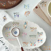 White ceramic plate decorated with colorful lantern designs and floral elements