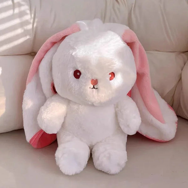 A white rabbit plush toy with pink ears sitting on a light surface.