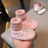 Pink knit bear booties for baby's first steps shown on a hand with other similar items.