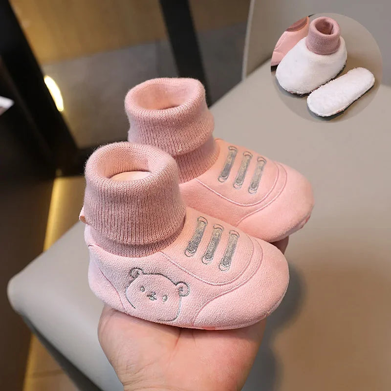 Pink knit bear booties for baby's first steps shown on a hand with other similar items.