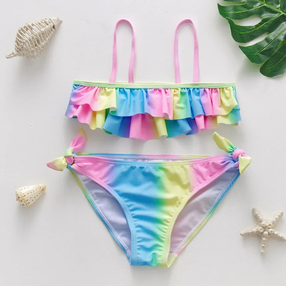 A girls two-piece rainbow swimsuit set featuring a ruffled top and matching bottoms.