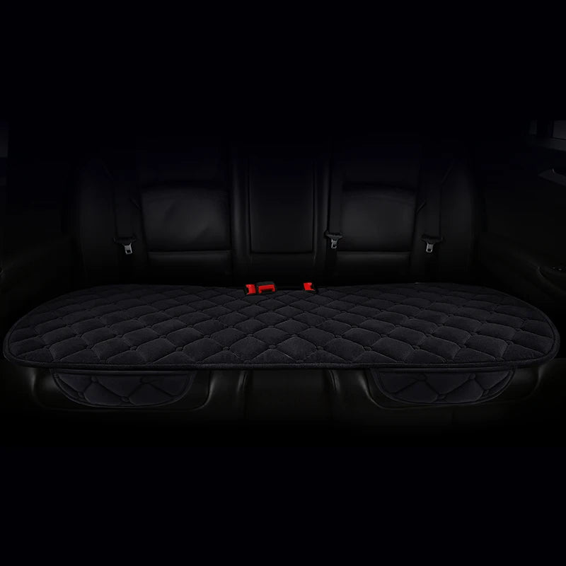 A set of three black plush anti-slip car seat cushions with quilted texture shown inside a vehicle interior.